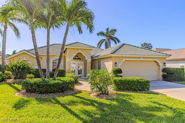 mediterranean / spanish house featuring a garage, a front yard, and french doors