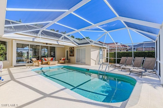 view of pool with outdoor lounge area, glass enclosure, and a patio area