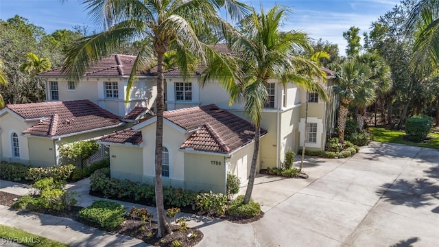 mediterranean / spanish home with driveway, stucco siding, a garage, and a tiled roof