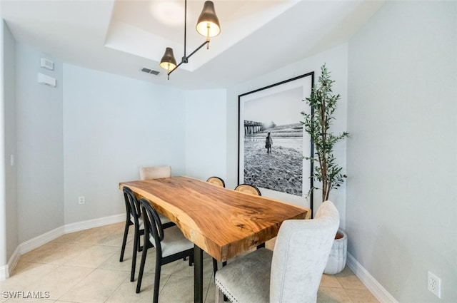 dining space featuring light tile patterned floors, a raised ceiling, visible vents, and baseboards