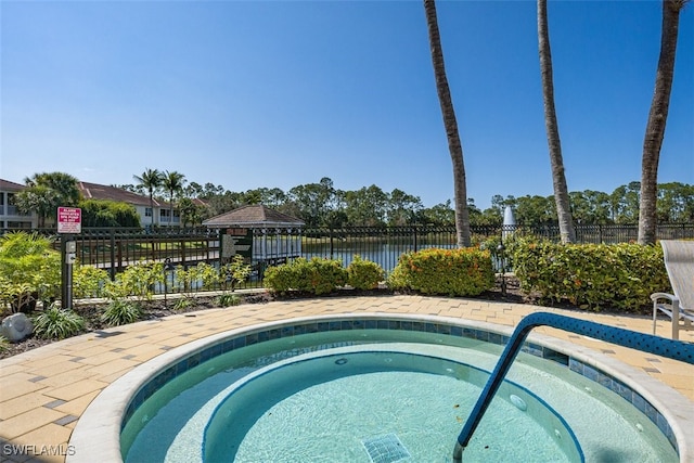 view of pool featuring a water view, fence, and a hot tub