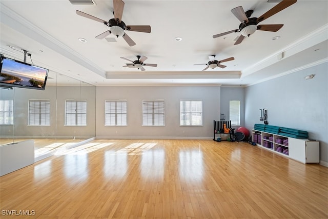 interior space with a raised ceiling, visible vents, ornamental molding, wood finished floors, and baseboards