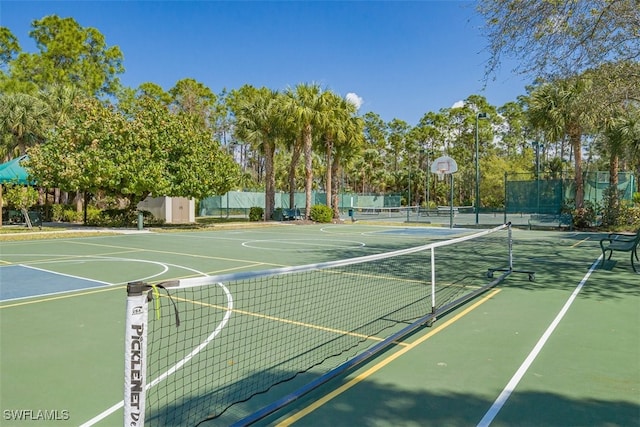 view of tennis court with community basketball court and fence