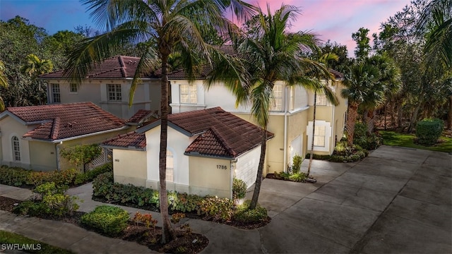 exterior space featuring concrete driveway, a tile roof, and stucco siding