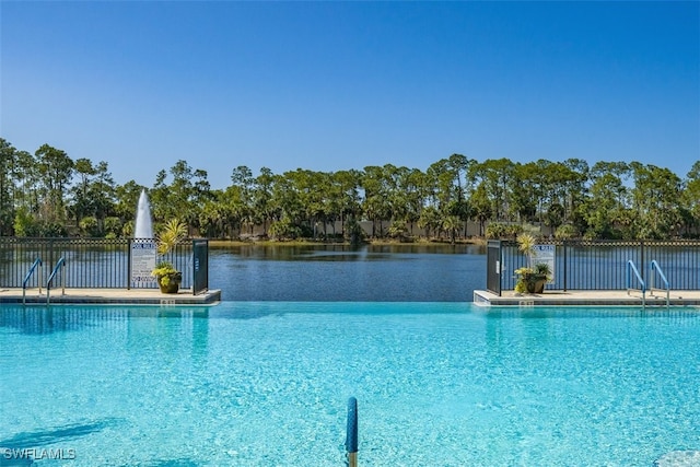 community pool with a water view and fence