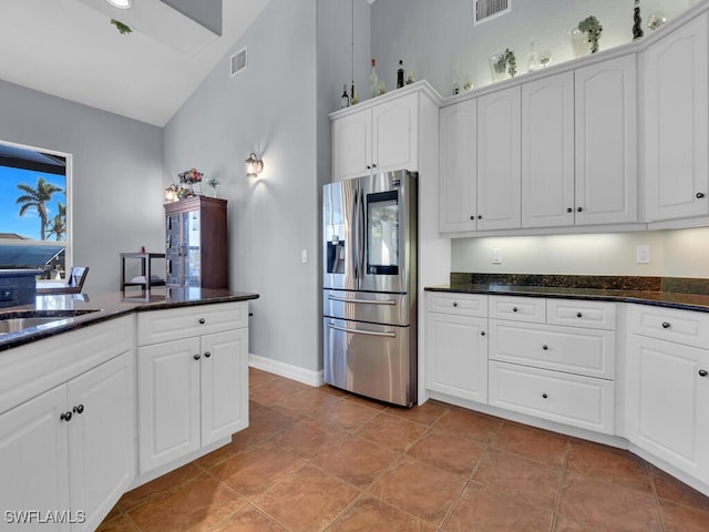 kitchen featuring light tile patterned flooring, white cabinetry, stainless steel refrigerator with ice dispenser, and dark stone counters