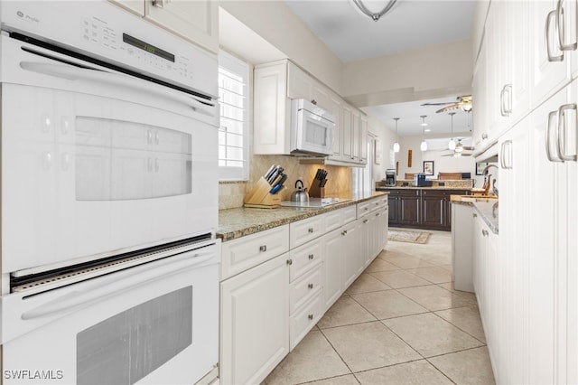 kitchen featuring white cabinets, decorative backsplash, white appliances, and light stone countertops