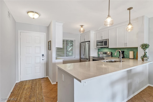 kitchen with kitchen peninsula, appliances with stainless steel finishes, sink, decorative light fixtures, and white cabinets