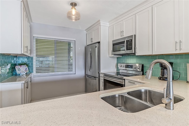 kitchen featuring light stone countertops, backsplash, stainless steel appliances, sink, and white cabinets