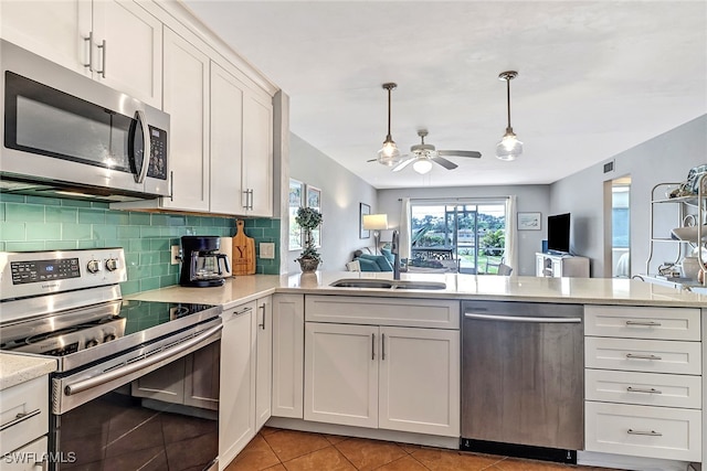 kitchen with sink, light tile patterned floors, pendant lighting, white cabinets, and appliances with stainless steel finishes