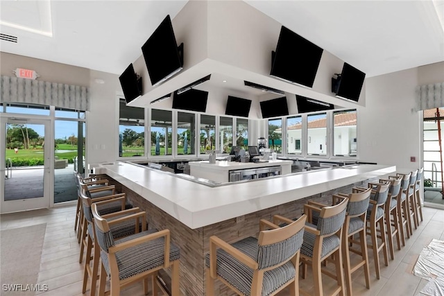 kitchen with a breakfast bar, light hardwood / wood-style floors, and a high ceiling