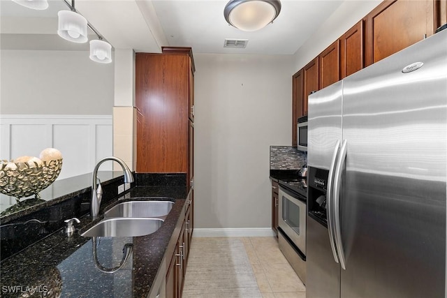 kitchen with dark stone counters, sink, decorative light fixtures, light tile patterned flooring, and stainless steel appliances