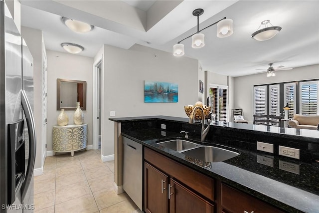 kitchen with dark stone counters, sink, ceiling fan, appliances with stainless steel finishes, and decorative light fixtures