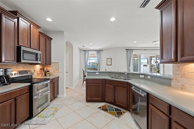 kitchen with backsplash, stainless steel appliances, a wealth of natural light, and sink