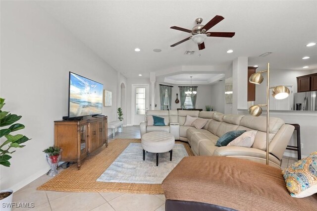 tiled living room featuring ceiling fan with notable chandelier