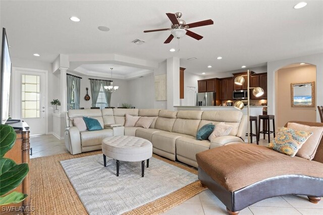 living room with light tile patterned floors and ceiling fan with notable chandelier