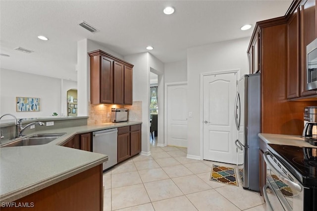 kitchen featuring sink, stainless steel appliances, kitchen peninsula, decorative backsplash, and light tile patterned floors