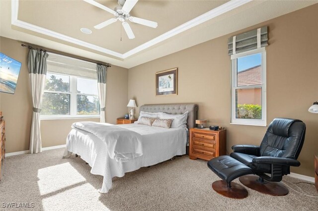 carpeted bedroom with a tray ceiling, ceiling fan, and ornamental molding