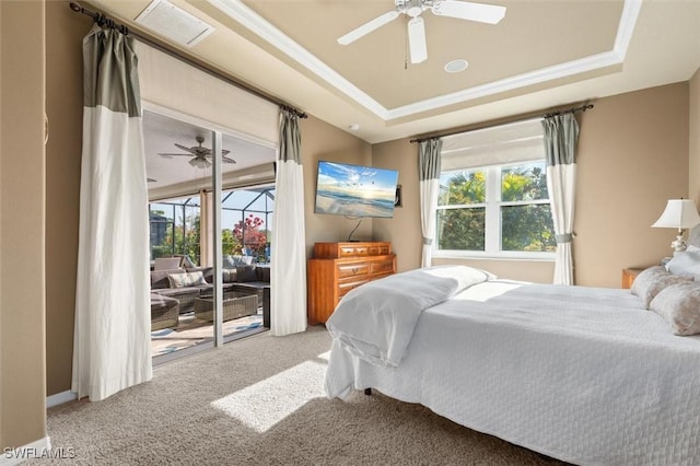 bedroom featuring access to outside, a tray ceiling, multiple windows, and carpet floors