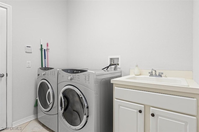 clothes washing area featuring cabinet space, light tile patterned floors, washer and clothes dryer, and a sink