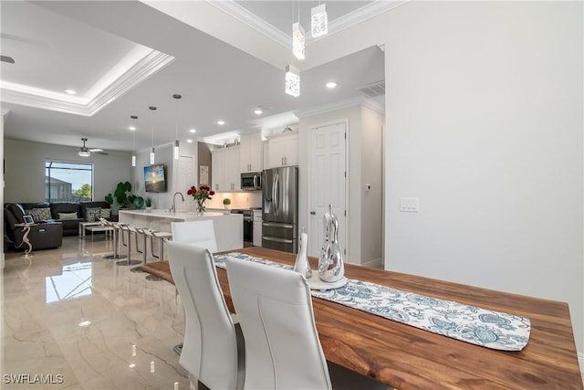 dining room featuring a raised ceiling, ceiling fan, crown molding, and sink