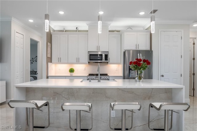 kitchen with pendant lighting, stainless steel appliances, white cabinetry, and an island with sink