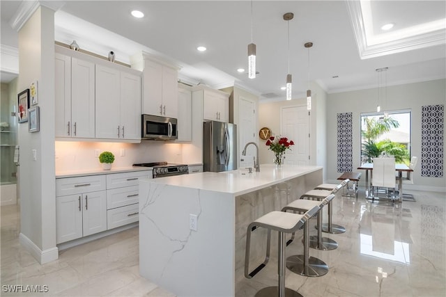 kitchen with white cabinetry, a kitchen island with sink, decorative light fixtures, and appliances with stainless steel finishes