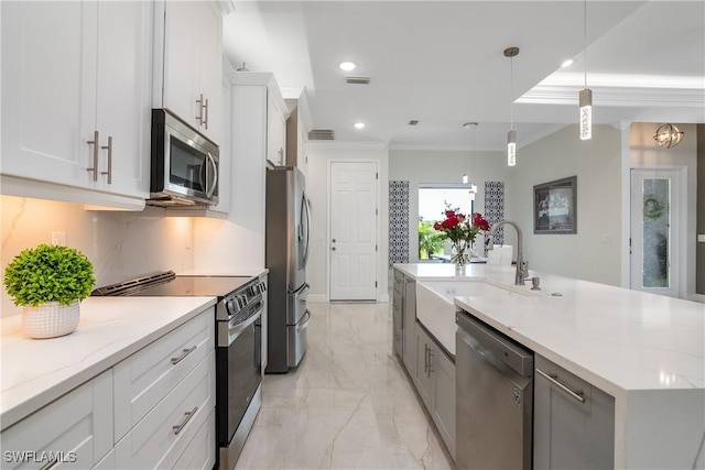 kitchen featuring decorative light fixtures, stainless steel appliances, white cabinetry, and an island with sink