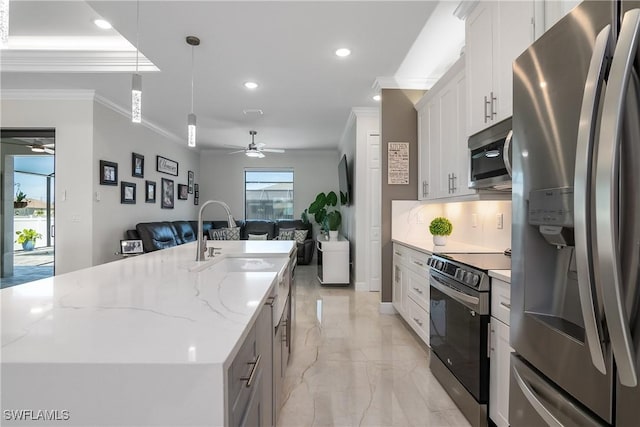 kitchen featuring white cabinetry, stainless steel appliances, light stone counters, decorative light fixtures, and a kitchen island with sink