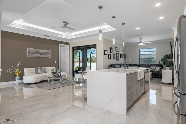 kitchen with decorative light fixtures, plenty of natural light, a center island with sink, and sink