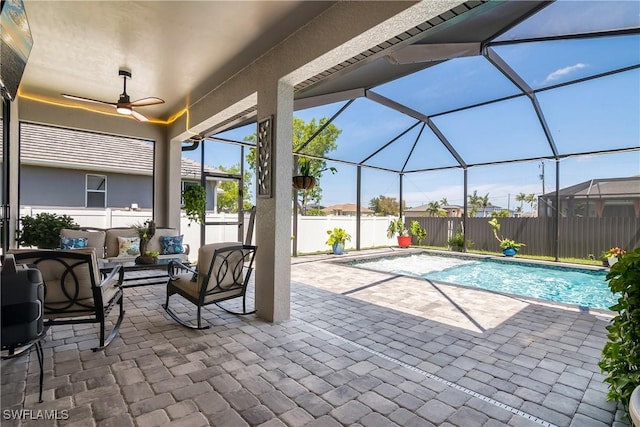 view of pool with outdoor lounge area, a patio, ceiling fan, and a lanai