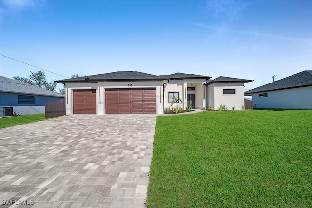 prairie-style home with a garage, a front yard, and central AC