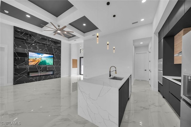 kitchen with light stone countertops, coffered ceiling, ceiling fan, sink, and decorative light fixtures