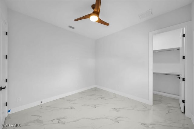 unfurnished bedroom featuring a spacious closet, a closet, and ceiling fan