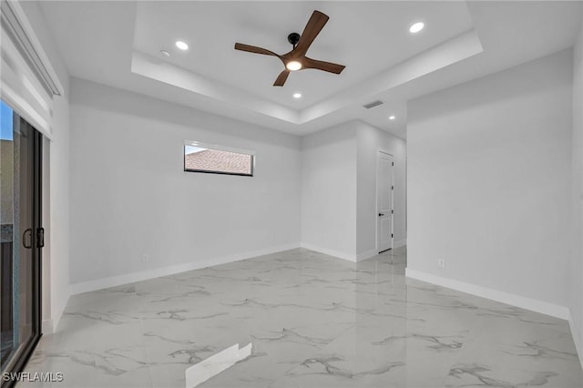 empty room with a raised ceiling and ceiling fan