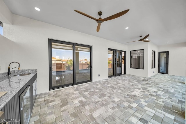 interior space with ceiling fan, beverage cooler, and sink