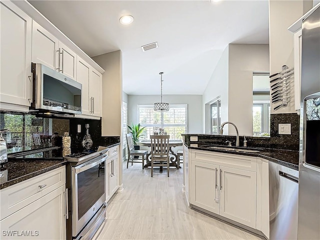 kitchen featuring backsplash, dark stone counters, sink, white cabinetry, and stainless steel appliances