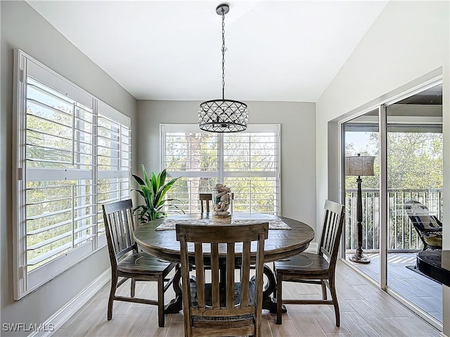 dining area featuring an inviting chandelier, light hardwood / wood-style flooring, and lofted ceiling