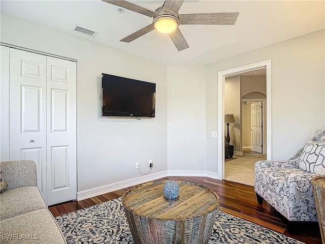 living room with ceiling fan and dark wood-type flooring