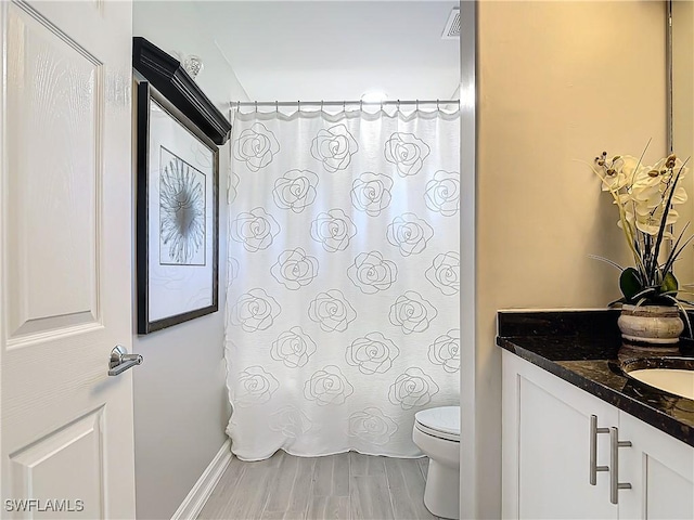 bathroom featuring vanity, wood-type flooring, and toilet