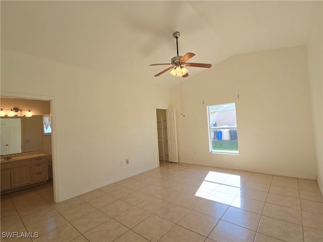 tiled empty room featuring ceiling fan, lofted ceiling, and sink