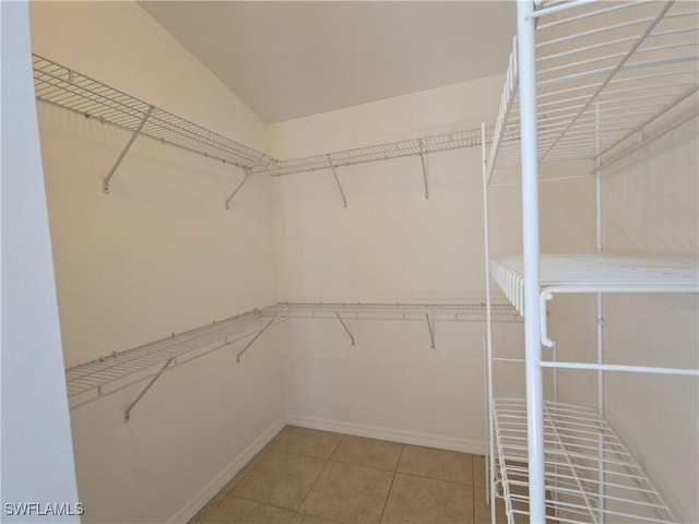 walk in closet with tile patterned flooring and lofted ceiling