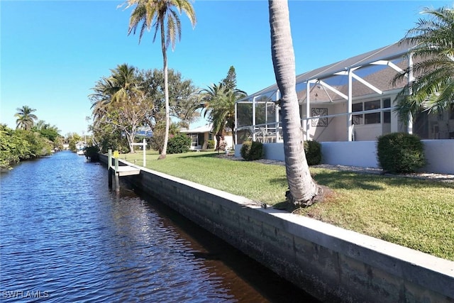 dock area featuring a water view, glass enclosure, and a lawn