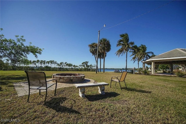 surrounding community featuring a fire pit, a gazebo, a water view, and a lawn