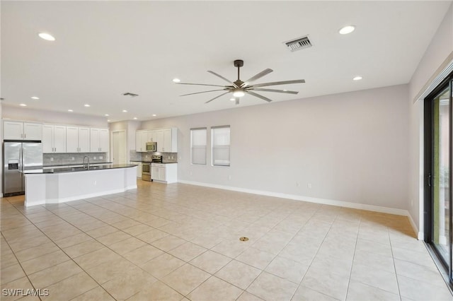 unfurnished living room with sink, light tile patterned floors, and ceiling fan