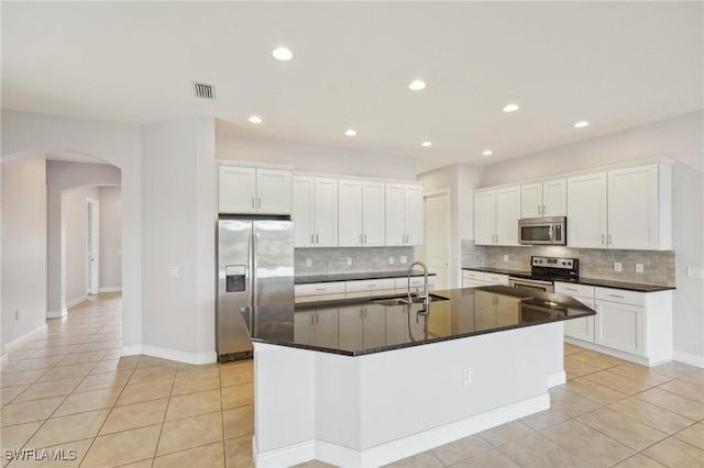 kitchen with light tile patterned flooring, sink, white cabinetry, a center island with sink, and appliances with stainless steel finishes