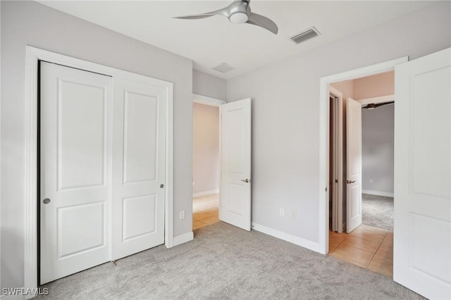 unfurnished bedroom with light carpet, ceiling fan, and a closet