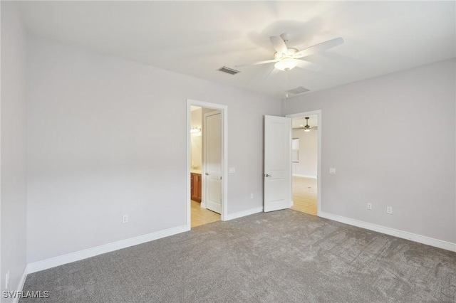 unfurnished bedroom featuring connected bathroom, light carpet, and ceiling fan