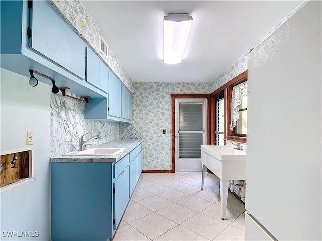 kitchen featuring sink, light tile patterned floors, and blue cabinets