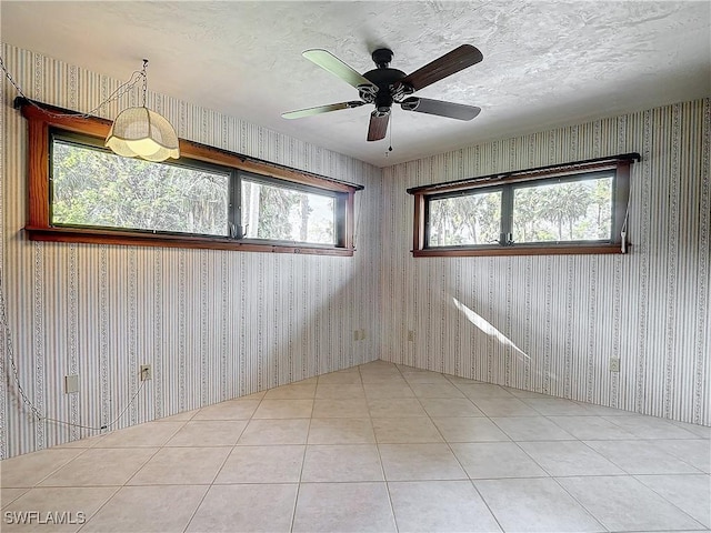 tiled empty room featuring ceiling fan and a textured ceiling